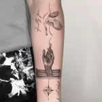 A fine-line tattoo featuring a hand reaching upward toward a flying dove, with the phrases "Finally free" and "Never give up."