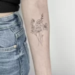 fine line tattoo with a lily, daffodil, lotus and iris on a woman's forearm.