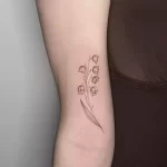 fine line lily of the valley tattoo on a woman's forearm