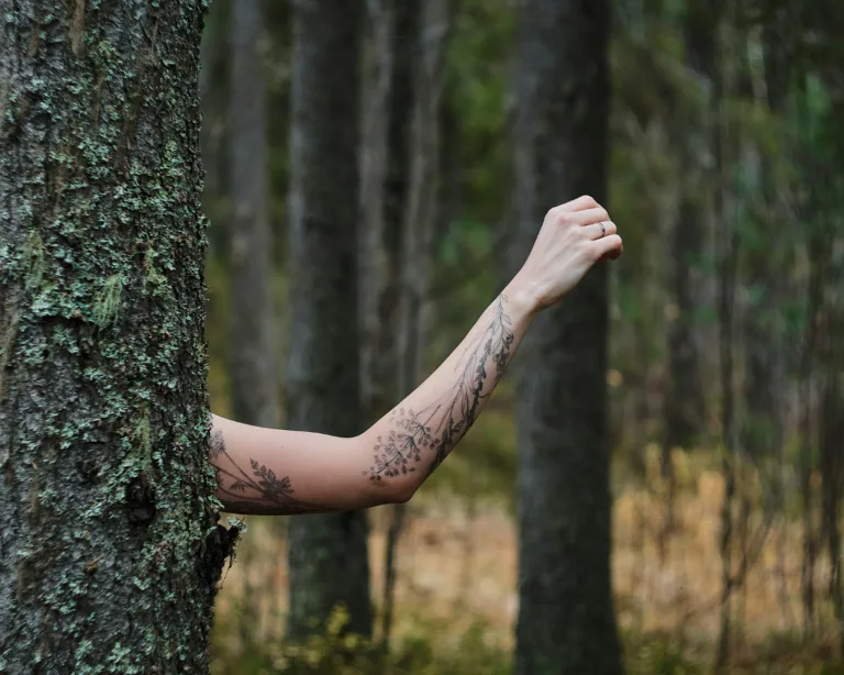 outdoor photo of a woman's arm with a flower tattoo